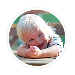 child with hands folded on table